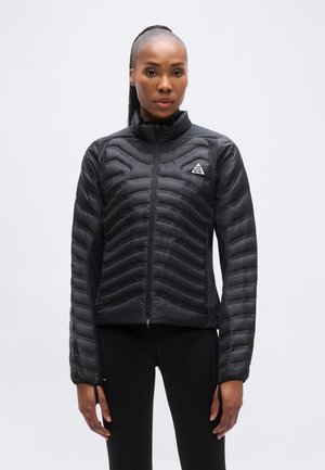 Giacca imbottita nera con trapuntatura orizzontale, collo alto, zip frontale e dettaglio logo. Finitura liscia e design aderente.