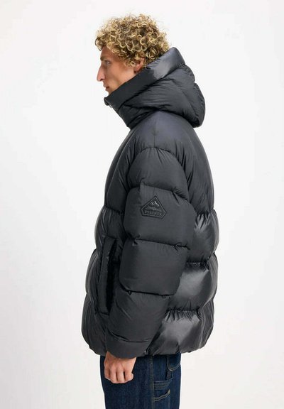 Giacca a piumino nera con collo alto, design trapuntato e toppa con logo sulla manica. Materiale morbido e lucido, isolante per il calore.