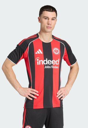Rood en zwart gestreept voetbalshirt met een ronde hals, korte mouwen en het Adidas-logo. Bevat het "indeed"-logo op de voorkant en het clubembleem.