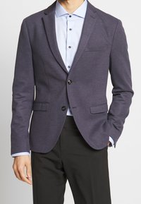 Námořnický blazer s texturou, s klopami, dvěma předními kapsami a dvěma knoflíky, spárovaný se světle modrou košili s kontrastními knoflíky.