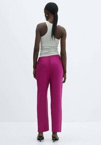 Fuchsia wijde broek met een relaxte fit, voorzien van een elastische tailleband en twee achterzakken, gecombineerd met een grijze tanktop.