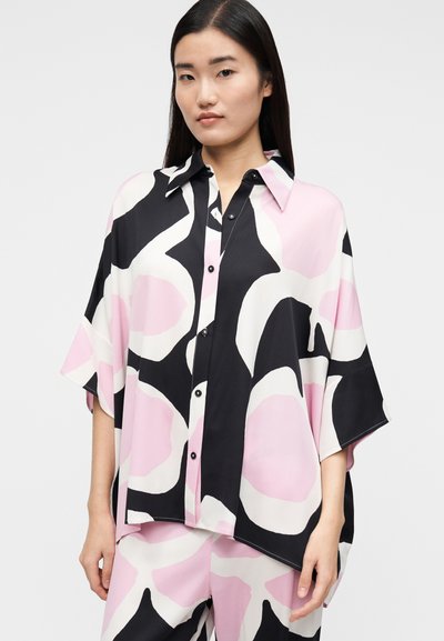 Lös sittande, kortärmad blus i svart med stora abstrakta rosa och vita former. Har knappstängning framtill och spetsig krage.