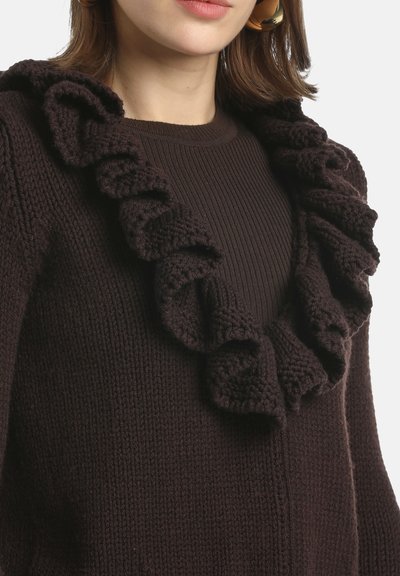 Ruskea neulottu villapaita, jossa on resorimainen vartalo ja koristeellinen röyhelöinen kaula-aukko. Kangas on teksturoitu ja malli istuva.