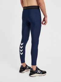 Marinblå leggings med en svart märkesmidja, med vita chevronmönster på vänster ben och en slät, åtsittande design.