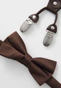 Nœud papillon en satin marron avec une texture lisse, accompagné de bretelles en cuir marron dotées de clips métalliques et de détails.