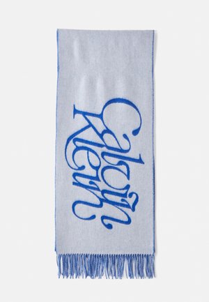Lyseblåt tørklæde med et stort, fedt blåt kursiv logo og frynser i kanten. Blødt materiale med en glat overflade.