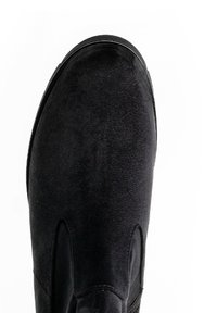 Zwarte suède enkelboot met een ronde neus, elastische zijpanelen en een gladde textuur. Subtiele stiksels zijn zichtbaar.