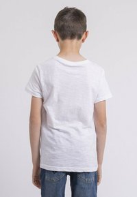 T-shirt blanc à manches courtes avec un col rond, présenté de dos. Tissu doux, coupe décontractée, associé à un jean en denim.