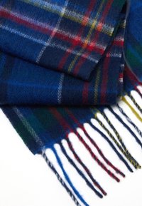 Bufanda de lana a cuadros en azul con acentos en rojo, verde y amarillo. Presenta bordes con flecos y una textura suave, con un patrón de espiga.