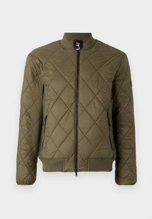 Jachetă bomber matlasată de culoare verde măsline, cu fermoar frontal, manșete ribbate și două buzunare laterale cu fermoar. Prezintă un design cu cusături în formă de diamant.