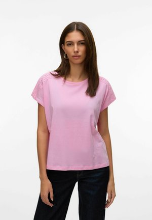 Rosa kurzärmliges Oberteil aus weicher Baumwolle mit rundem Hals und Spitzenverzierungen an den Schultern. Kombiniert mit dunklen Jeans.