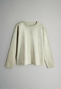 Šviesiai smėlio spalvos ilgomis rankovėmis marškinėliai su apvalia iškirpte, pagaminti iš minkštos medžiagos, pasižymintys laisvu pavyzdžiu ir minimalistiniu dizainu be matomų raštų.