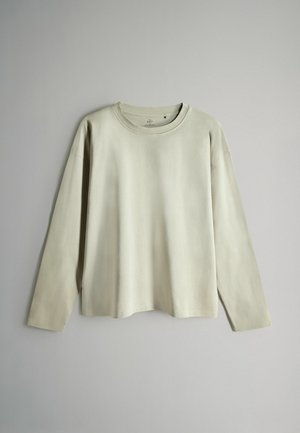 Šviesiai smėlio spalvos ilgomis rankovėmis marškinėliai su apvalia iškirpte, pagaminti iš minkštos medžiagos, pasižymintys laisvu pavyzdžiu ir minimalistiniu dizainu be matomų raštų.