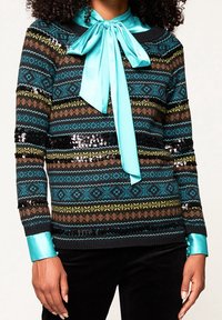 Sweter z dzianiny z wzorowanym deseniem w czarne, turkusowe, żółte i brązowe paski; zawiera turkusową satynową kokardę i mankiety.