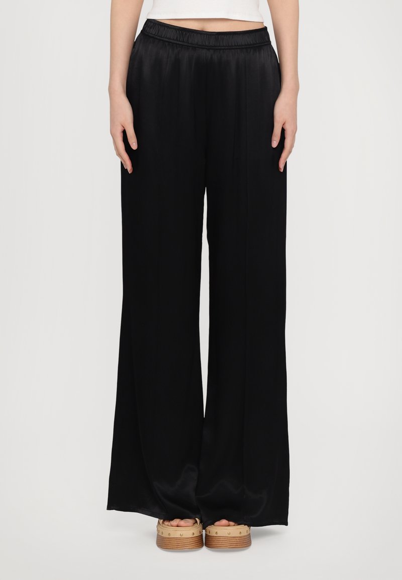 Pantalons noirs à jambes larges en tissu lisse et léger avec une taille élastique, présentant un design fluide et un éclat subtil.
