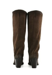 Stivali di camoscio marroni al ginocchio con una texture liscia, tacco squadrato e linee pulite, caratterizzati da un design semplice senza modelli o decorazioni notevoli.