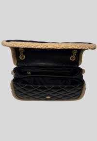 Borsa in pelle nera trapuntata con bordi in pelliccia, hardware dorato e un ampio interno con più scomparti e una tasca con zip.