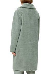 Manteau en polaire texturé vert avec un large col et des manches longues, présentant une silhouette droite et un tissu doux et moelleux.