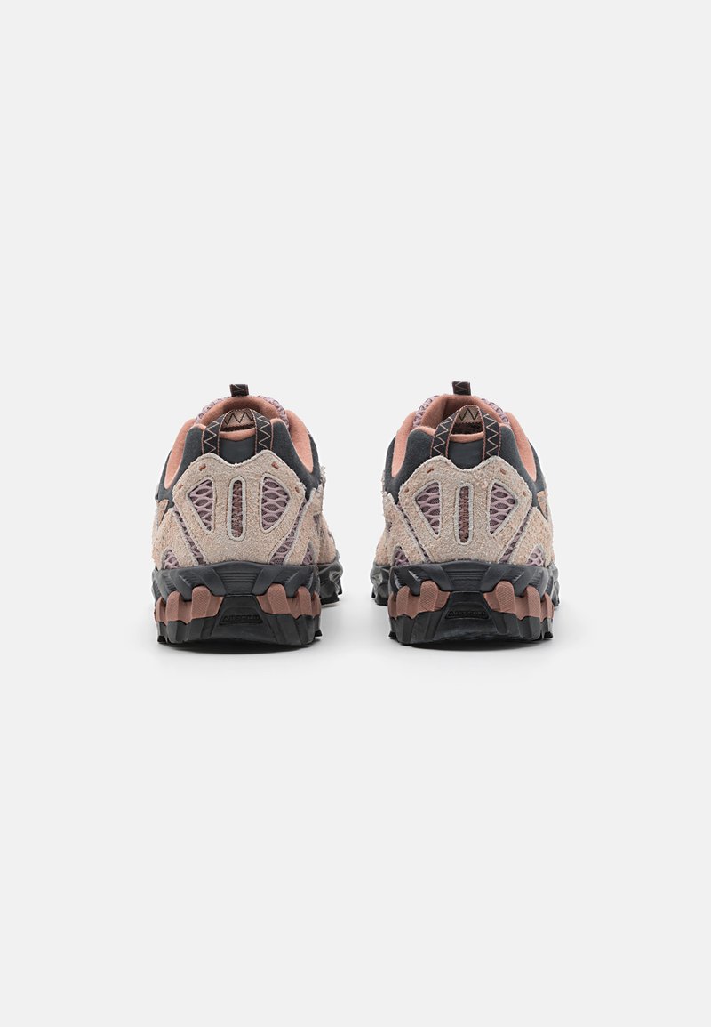 Chaussures de randonnée avec une tige beige clair, des accents en mesh, une semelle en caoutchouc noire et des touches de rose. Présente un talon protecteur et un design texturé.