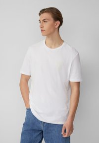 Weißes Baumwoll-T-Shirt mit rundem Ausschnitt und kurzen Ärmeln, das auf der Brust ein dezentes grafisches Logo in hellgelb zeigt.