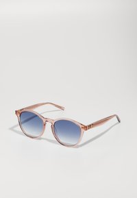 Lunettes de soleil rondes avec des verres dégradés bleus et une monture translucide rose. Comporte des accents dorés sur les branches et des embouts argentés.