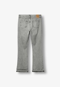 Jean denim gris clair avec jambes droites, deux poches arrière et un patch de marque en cuir marron sur la ceinture.