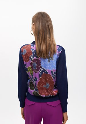 Maglione blu navy con un motivo floreale in rosso, blu e verde sulla schiena; presenta maniche lunghe e polsini a costine.