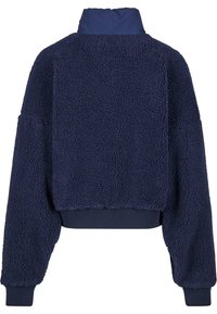 Marinblå korttröja i texturerad fleece. Har en hög krage och ribbade ärmslut. Mjukt och mysigt material med en oversized passform.