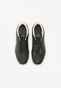 Black leather sneakers with white accents, featuring a textured surface, round toe, lace-up closure, and branded insole.