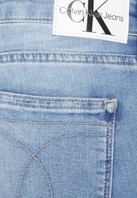 Ljusblå denimjeans med en synlig bakficka. Funktioner en Calvin Klein-tag med en svart logotyp och kontrasterande sömnad.