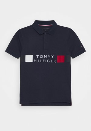 Marineblaue Polohemd mit kurzen Ärmeln, Kragen, zwei Knöpfen und weißen sowie roten rechteckigen Akzenten rund um den Schriftzug "TOMMY HILFIGER" auf der Brust.