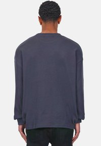 Sudadera de manga larga, de canalé, en gris oscuro con cuello redondo y corte relajado, que presenta hombros caídos y un dobladillo curvado.
