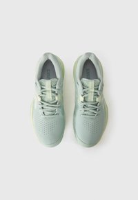 Baskets de sport vert clair avec un dessus en maille texturée, un design perforé, des lacets plats et une semelle légèrement translucide.