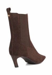 Brown suede ankle boot with a pointed toe, elastic side panels, and a tapered heel. Features a decorative gold accent at the top.