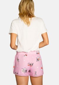 Roze shorts van zacht materiaal met verschillende hondenillustraties en pootafdrukken. De tailleband is elastisch voor comfort en gemak bij het dragen.