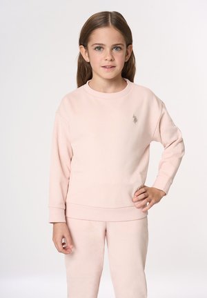 Felpa rosa chiaro in tessuto morbido, con scollo rotondo, maniche lunghe e piccolo logo sul petto. Presentata con pantaloni coordinati.