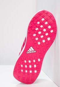 Jasně růžová podrážka běžecké boty Adidas s texturovanými čtvercovými vzory, bílými výřezy a štítkem "neznačkovací" na bílém pozadí.
