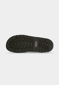 Semelle de chaussure en caoutchouc noir avec des motifs de profondeur et le nom de la marque Keen centré sur la semelle.