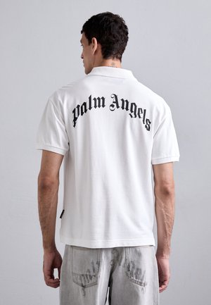 White short-sleeve polo shirt featuring black Gothic text "Palm Angels" on the back. Cotton material with a classic collar design.