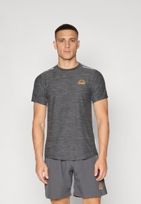 Grå treningst-t-skjorte med horisontal tekstur, som har en liten oransje logo og hvite striper på skuldrene, kombinert med grå shorts.