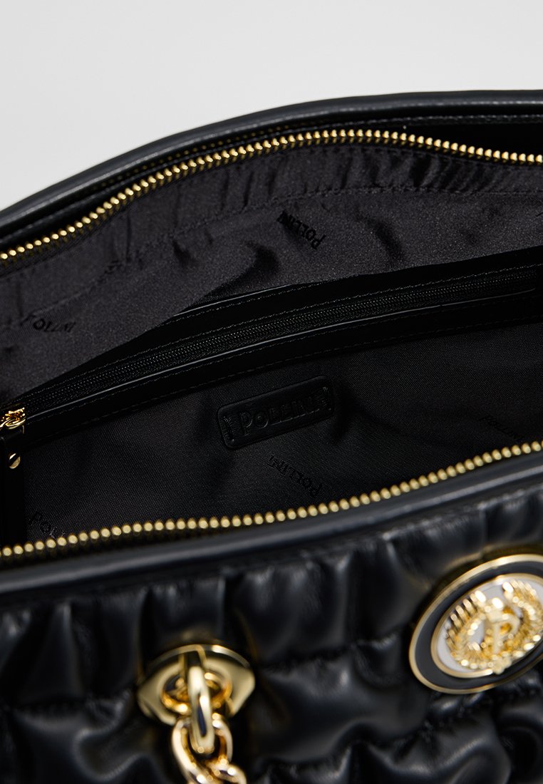 Borsa a tracolla nera trapuntata con dettagli in oro. L'interno foderato presenta una tasca con zip. L'etichetta interna mostra il nome del brand su una superficie liscia.