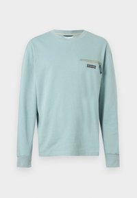 Ανοιχτό μπλε μακρυμάνικο μπλουζάκι με στρογγυλή λαιμόκοψη, μικρή τσέπη με φερμουάρ και το λογότυπο Columbia στην αριστερή πλευρά του στήθους.