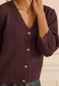 Bordeaux gebreide cardigan met V-hals, voorzien van drie decoratieve, sneeuwvlokvormige knopen en geribde mouwen en onderrand.