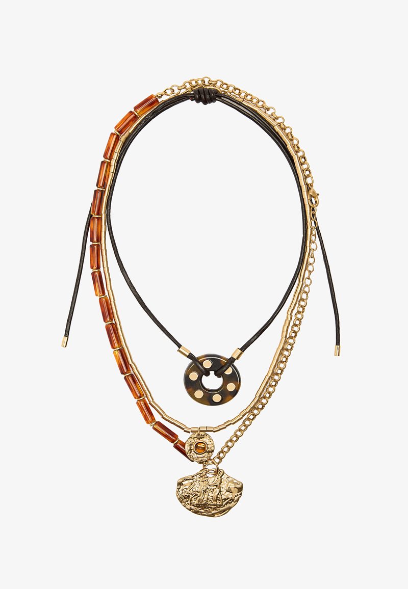 Naszyjnik warstwowy z łańcuszkami w kolorze złotym, teksturowanymi bursztynowymi koralikami oraz okrągłą czarną zawieszką z otworami, a także złotym przywieszką z detalicznym wzorem.
