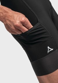 Schwarze Sportshorts aus glattem Stoff, ausgestattet mit einer Seitentasche und einem kontrastierenden weißen Logo, im figurbetonten Design und mit flachen Nähten.