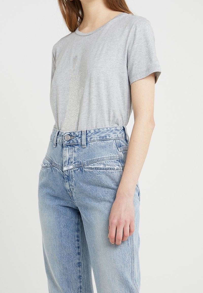 Grå bomullströja med korta ärmar och en texturerad design. Kombinerad med ljusblå högmidjade jeans med blekta detaljer.