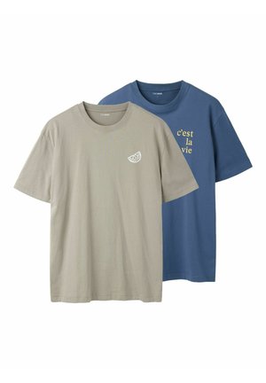 Deux t-shirts à manches courtes et col rond, un beige avec une petite tranche blanche de citron, un bleu avec un texte jaune « c’est la vie » sur le devant.