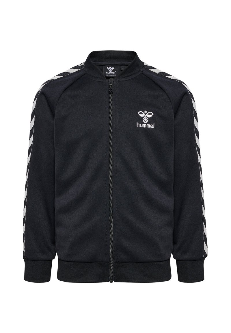 Veste zippée noire avec col montant, mettant en avant des rayures blanches diagonales sur les épaules et un petit logo sur la poitrine. Texture de tissu douce.