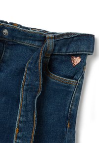 Denim jeans in een blauwe kleur, met een gestrikte taille, oranje stiksels en een klein metalen hartvormig detail op de zak.