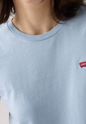 Vaaleansininen puuvillapaita, jossa on pyöreä kaula-aukko ja vasemmassa rinnassa pieni punainen Levi's-logo.